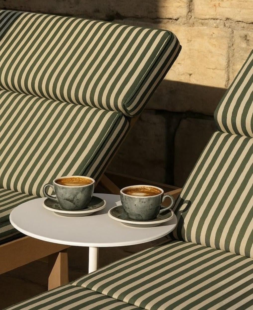 Twee koppen koffie tussen gestreepte ligbedden